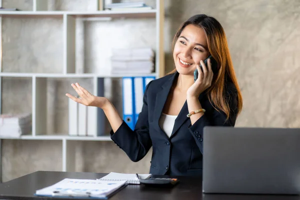 stock image Serious asian businesswoman using customer service phone sitting at table, sales manager focused woman on mobile business phone discussing work with customer in office