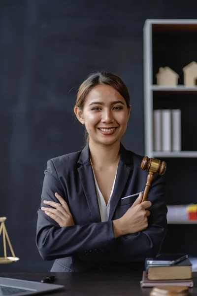 Female lawyer holding hammer crossed arms, legal consultant sitting in law office Female lawyer sitting with her arms crossed smiling happily in the concept of justice law. Portrait image.