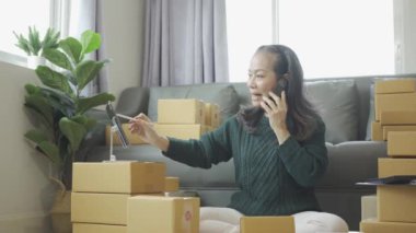Olgun bir kadın iş kuruyor, KOBİ sahibi, bayan girişimci çalışıyor ve evdeki tablet dizüstü bilgisayarla online siparişi kontrol ediyor. KME iş konsepti çevrimiçi paket teslimatı 4k