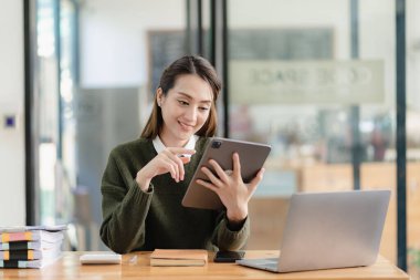 Dost canlısı ve mutlu Asyalı kadın dizüstü bilgisayar kullanıyor ve sohbet ediyor. Evde online iş görüşmesine bir video konferansı düzenle