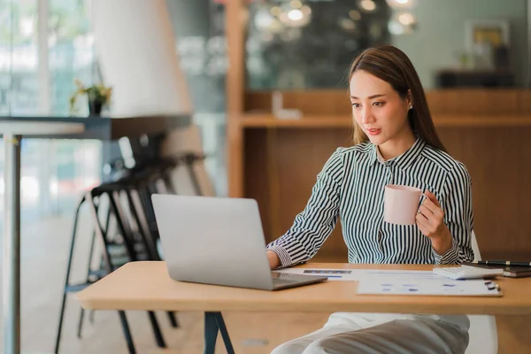 stock image Smiling Asian businesswoman working on tablet computer at her desk in bright modern office Calculating financial report expenses with graph documents