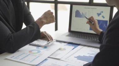 Finansal analist, şirket toplantısında başarılı takım çalışmalarını tartışırken iş finans raporunu grafik kağıdında analiz ediyor. 4k