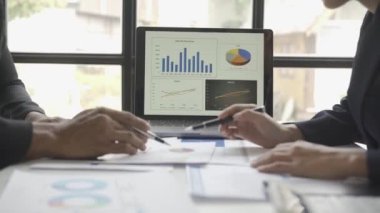 Finansal analist, şirket toplantısında başarılı takım çalışmalarını tartışırken iş finans raporunu grafik kağıdında analiz ediyor. 4k