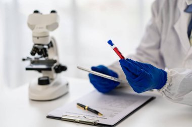 Tıbbi araştırmacı ve mavi lateks eldivenler mikropları önlemek için bir hastanın kan damarlarının laboratuardaki araştırma deneylerine götürüldüğünü gösteriyor..
