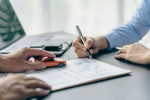 Salesman guiding customer seated at table. Car business. Car sale. Dealership closing. and the new owner has entered into a contract The idea of selling and renting a car with insurance.