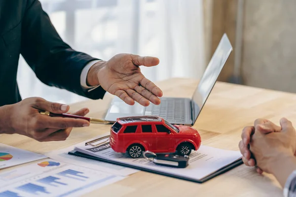 Salesman guiding customer seated at table. Car business. Car sale. Dealership closing. and the new owner has entered into a contract The idea of selling and renting a car with insurance.