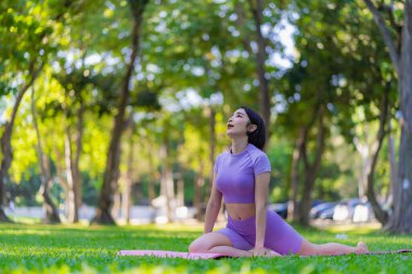 Genç Asyalı kadın egzersiz ve sağlık için bahçede yoga yapıyor. Parkta Asyalı kadın yoga yapıyor ve yazın yeşil parkta spor kıyafetleriyle rahatlıyor.