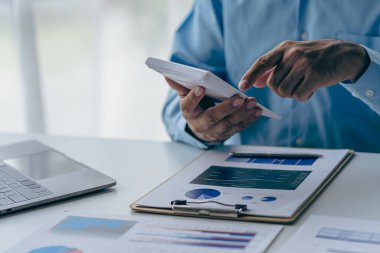 Muhasebeci, ofis muhasebe konseptindeki finans raporunu hesaplamak için hesap makinesini kullanır, iş adamı ise ofiste bilgisayar, bütçe ve kredi kağıdı kullanarak hesap makinesi kullanır..