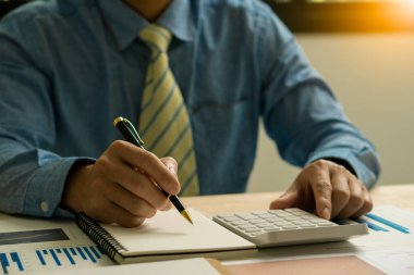 Muhasebeci elinde kalem tutuyor ve ofis vergisi, muhasebe, istatistik ve analitik araştırma konsepti, iş finansmanı gibi ahşap masa üzerinde şirket vergisi yapıyor.