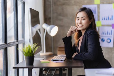 İnternette çalışan ve dizüstü bilgisayar ve mali belgelerle finansal veri planlayan Asyalı kadın, ev işkadını ve finans planlamacısı