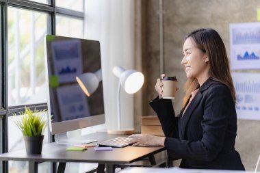 İnternette çalışan ve dizüstü bilgisayar ve mali belgelerle finansal veri planlayan Asyalı kadın, ev işkadını ve finans planlamacısı