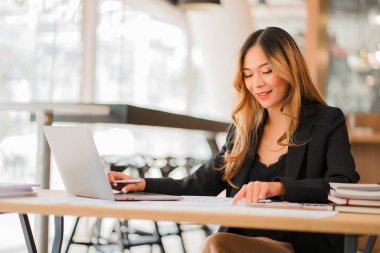 Masada dizüstü bilgisayarla çalışan iş kadını Asyalı kadın muhasebeci ya da bankacı ofisteki finans ve finans ekonomisi kavramını hesaplıyor.