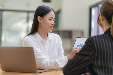 İş kadını, iş arkadaşlarının önünde sunum yapıyor. İş kadını danışman, şirket grup eğitiminde finansal tabloları, dizüstü bilgisayarları ve finansal evrakları açıklıyor.