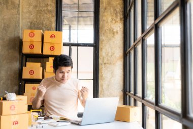 Asyalı bir adam internetten bilgisayarla, internet üzerinden ve e-ticaretle müşteri siparişi alıyor. Ev ürünleri sat