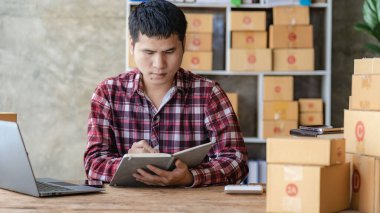 Asyalı bir adam internetten bilgisayarla, internet üzerinden ve e-ticaretle müşteri siparişi alıyor. Ev ürünleri sat