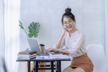 İş yerinde dizüstü bilgisayar kullanan güzel bir Asyalı kadın muhasebeci olarak ofis işine odaklan.