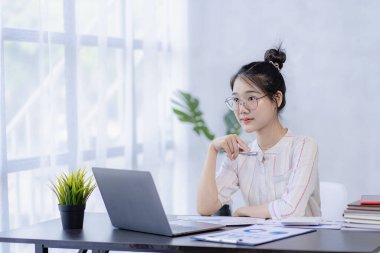 İş yerinde dizüstü bilgisayar kullanan güzel bir Asyalı kadın muhasebeci olarak ofis işine odaklan.
