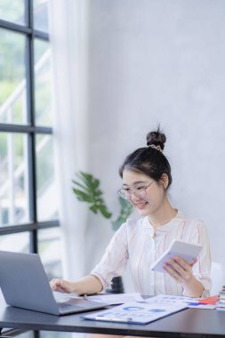 İş yerinde dizüstü bilgisayar kullanan güzel bir Asyalı kadın muhasebeci olarak ofis işine odaklan.