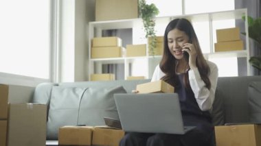 Ev telefonlu, bilgisayarlı, tabletli, güverteli (KOBİ) akıllı telefonlu kadın girişimci. Asyalı kadınların evde müşteri siparişlerini kontrol etmesi, müşterilere mal teslimatı..
