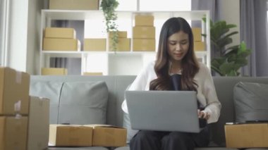 Ev telefonlu, bilgisayarlı, tabletli, güverteli (KOBİ) akıllı telefonlu kadın girişimci. Asyalı kadınların evde müşteri siparişlerini kontrol etmesi, müşterilere mal teslimatı..