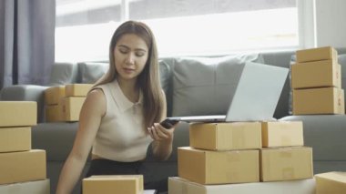 Ev telefonlu, bilgisayarlı, tabletli, güverteli (KOBİ) akıllı telefonlu kadın girişimci. Asyalı kadınların evde müşteri siparişlerini kontrol etmesi, müşterilere mal teslimatı..