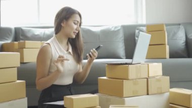 Ev telefonlu, bilgisayarlı, tabletli, güverteli (KOBİ) akıllı telefonlu kadın girişimci. Asyalı kadınların evde müşteri siparişlerini kontrol etmesi, müşterilere mal teslimatı..