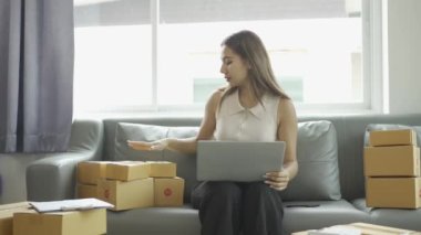 Ev telefonlu, bilgisayarlı, tabletli, güverteli (KOBİ) akıllı telefonlu kadın girişimci. Asyalı kadınların evde müşteri siparişlerini kontrol etmesi, müşterilere mal teslimatı..