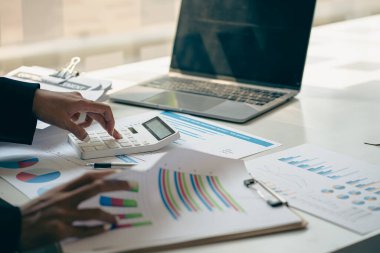 Belgelerle, mali grafiklerle ve faturalarla çalışan iş yerinde dizüstü bilgisayarla muhasebe hesaplarını uzaktan analiz eden bir işadamı..