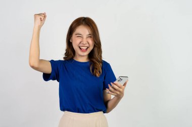 Mutlu Asyalı portresi, güzel tatlı genç bir kadın beyaz arka planda izole edilmiş akıllı telefon stüdyosunu heyecanlı bir şekilde kullanıyor..