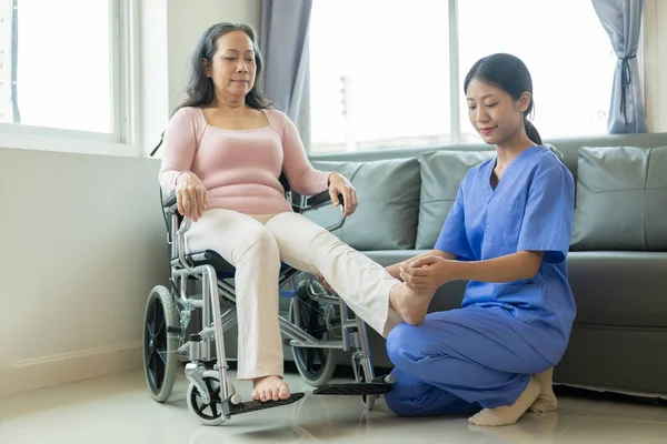 stock image Happy senior woman exercising at home with muscle physiotherapist Retired elderly woman stretching arms and legs at home with personal trainer