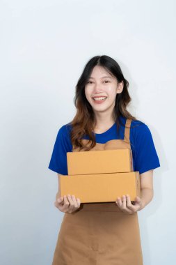 Sarı karton kutulu güzel heyecanlı Asyalı kadın izole beyaz arka planda duruyor. Kurye servisinden paket kutusu alan neşeli bir kadın, online alışveriş konsepti