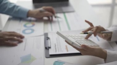 İstatistiksel analiz planı toplantısına katılan iki Asyalı işadamı ve takım lideri dizüstü bilgisayarlı grafiklere işaret ederek finansal başarı istatistikleri kavramını not alıyor. 4k video