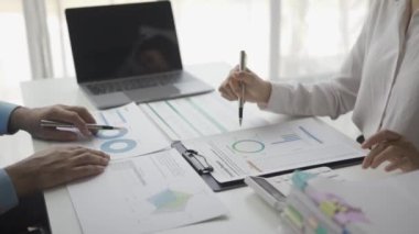 İstatistiksel analiz planı toplantısına katılan iki Asyalı işadamı ve takım lideri dizüstü bilgisayarlı grafiklere işaret ederek finansal başarı istatistikleri kavramını not alıyor. 4k video