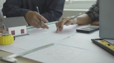İnşaat mühendisi ekibi mimar ve ustabaşıyla birlikte Mavi Yazıcı 'ya bakın ve binanın inşaatını planlayın. Ofiste, masa 4k 'nin üzerinde aletlerle.