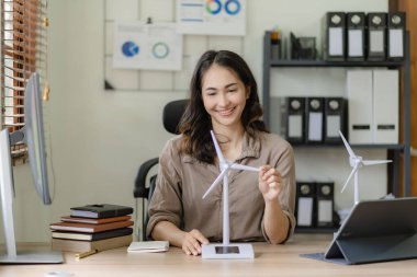 Çevre inşaatında çalışan güzel Asyalı kadın mimarın portresi, yel değirmeni modelini tutan ve ona bakan genç bir kadın işçi.