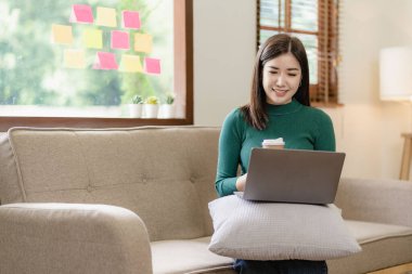 Güzel Asyalı kadın iş hakkında konuşmak için dizüstü bilgisayar kullanıyor evde internet üzerinden iyi iş çıkarıyor.