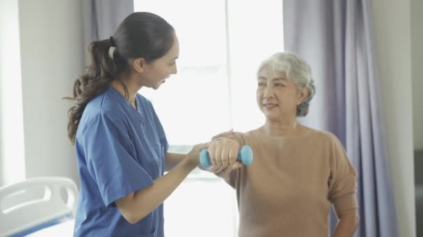 Jonge Vrouwelijke Fysiotherapeut Praat Toont Armbewegingen Aan Grijsharige Oude Vrouw — Stockvideo