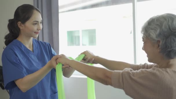 Jonge Vrouwelijke Fysiotherapeut Praat Toont Armbewegingen Aan Grijsharige Oude Vrouw — Stockvideo