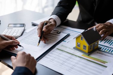 Emlakçı, emlakçıyla sözleşme imzalamak için müşteriye el ele tutuşuyor. Müşterinin kontrat belgelerini imzalamasına yardım ediyor. Sigorta kavramı.