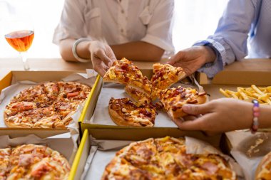 Meslektaşlar pizza partisinde öğle yemeği yer, çeşitli pizzalar yer ve kırsal ahşap masada kırmızı şarap içerek fast food öğle yemeğini kutlarlar.