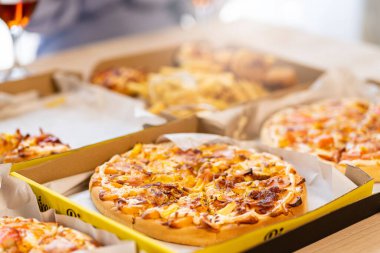 Meslektaşlar pizza partisinde öğle yemeği yer, çeşitli pizzalar yer ve kırsal ahşap masada kırmızı şarap içerek fast food öğle yemeğini kutlarlar.