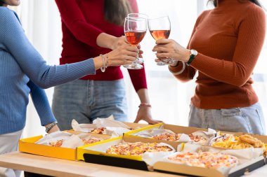 Meslektaşlar pizza partisinde öğle yemeği yer, çeşitli pizzalar yer ve kırsal ahşap masada kırmızı şarap içerek fast food öğle yemeğini kutlarlar.