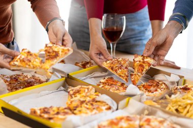 Meslektaşlar pizza partisinde öğle yemeği yer, çeşitli pizzalar yer ve kırsal ahşap masada kırmızı şarap içerek fast food öğle yemeğini kutlarlar.