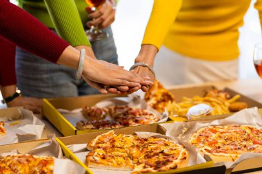 Meslektaşlar pizza partisinde öğle yemeği yer, çeşitli pizzalar yer ve kırsal ahşap masada kırmızı şarap içerek fast food öğle yemeğini kutlarlar.