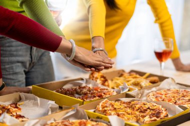 Meslektaşlar pizza partisinde öğle yemeği yer, çeşitli pizzalar yer ve kırsal ahşap masada kırmızı şarap içerek fast food öğle yemeğini kutlarlar.