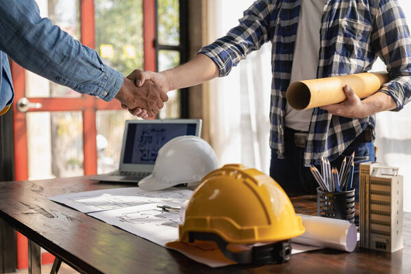 Construction workers holding helmets and vests are shaking hands. real estate concept Architect shaking hands with engineer or builder planning and successful meetings