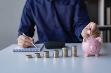 İşadamı, bankacılık, yatırım ve mali istikrar konularında banka ve kumbaranın önemi gibi madeni paralarla birikimlerini hesaplıyor.
