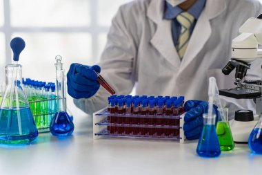 Analiz için kan damarlarını tutan ve laboratuvardaki kan örneklerini laboratuvarda analiz cihazıyla inceleyen doktor.