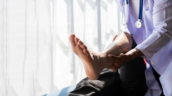 stock image Medical physiotherapist working on male patient's injured leg and treating male athlete patient's injured knee in clinic.