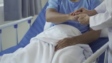 Hastaneden taburcu olduktan sonra hastaları sağlığına dikkat etmeye teşvik etmek için genç erkek hastaları ziyaret eden mutlu bir doktor.